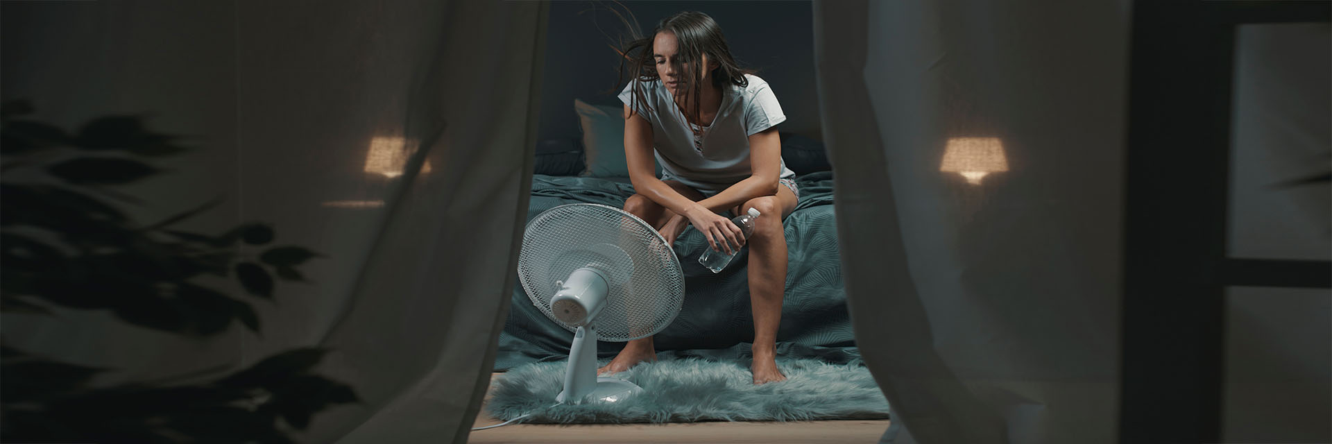 Woman sitting on bed in front of the fan 