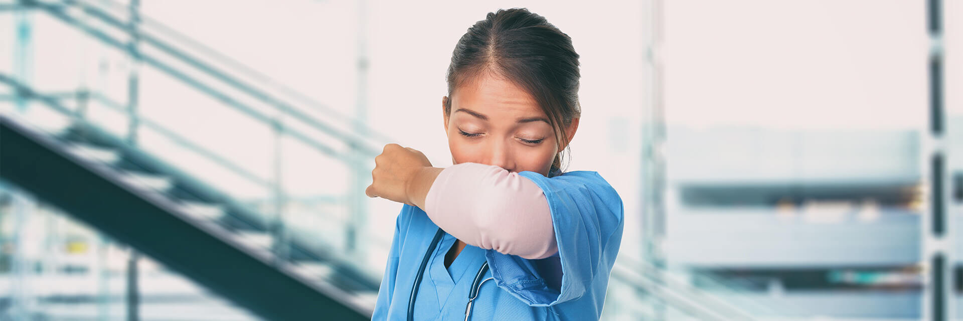 Woman sneezing into her elbow