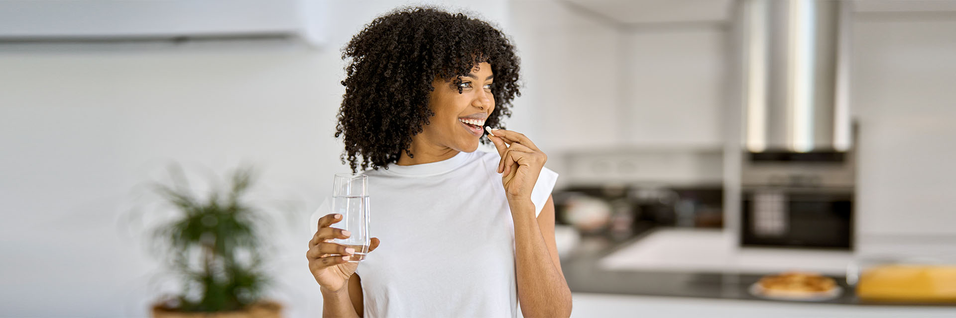 Young woman in the kitchen taking a capsule
