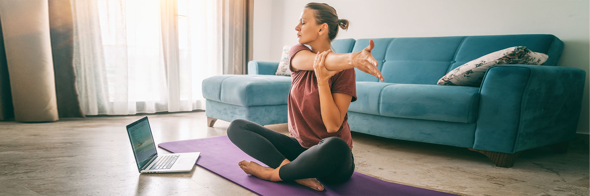 Woman doing yoga on the floor in front of her computer