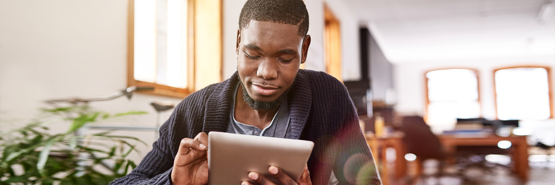 Man sitting reading tablet indoors