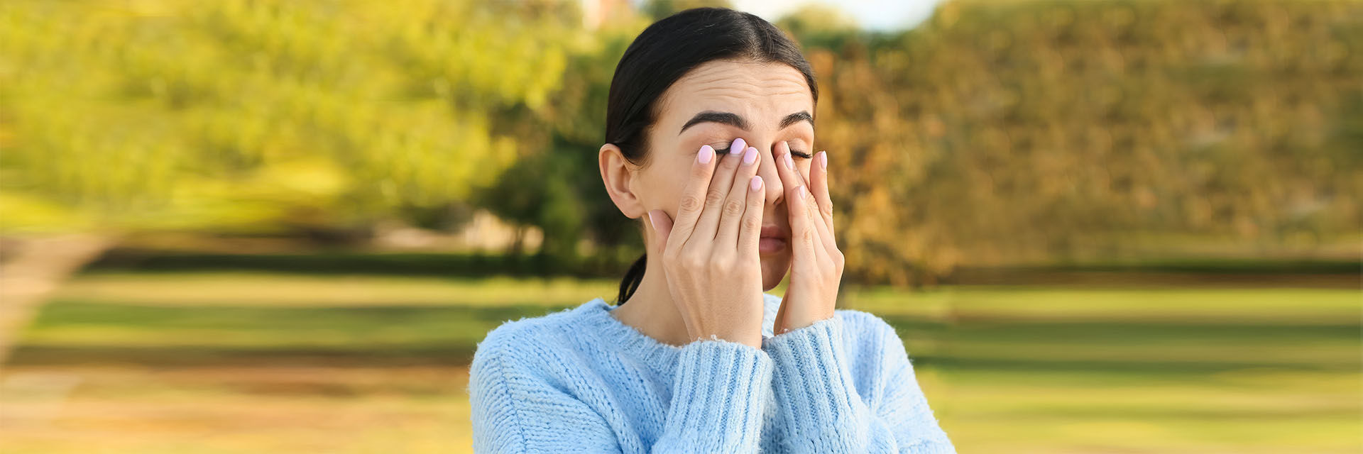 Woman holding her eyes outdoors
