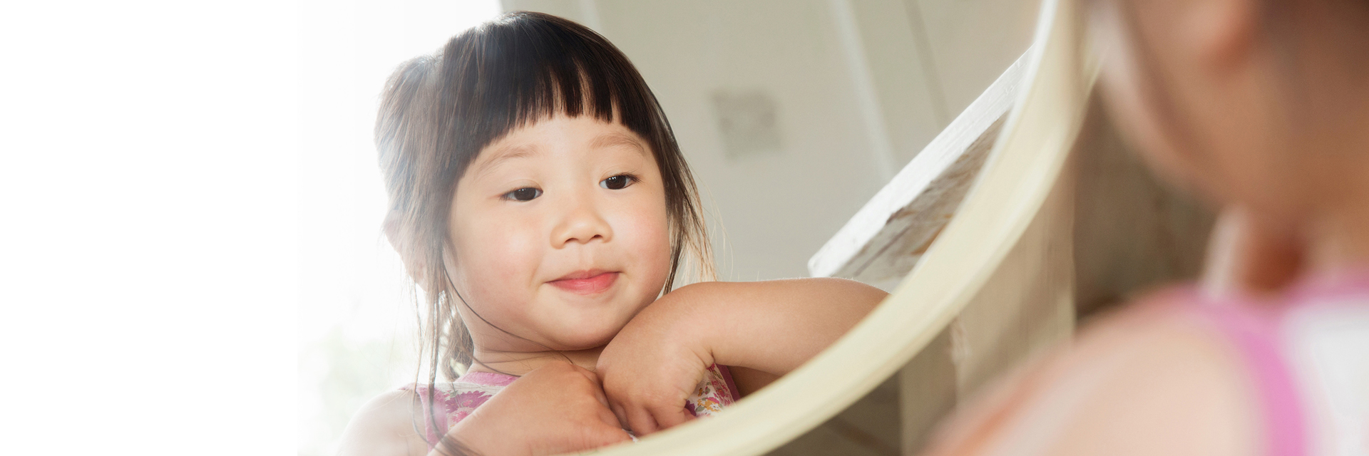 Little girl looking at herself in mirror