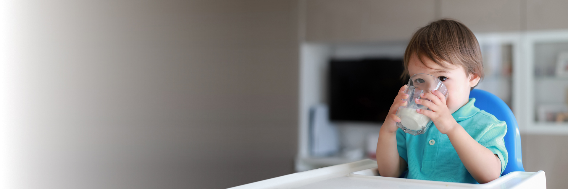 Little boy drinking from cup in high chair