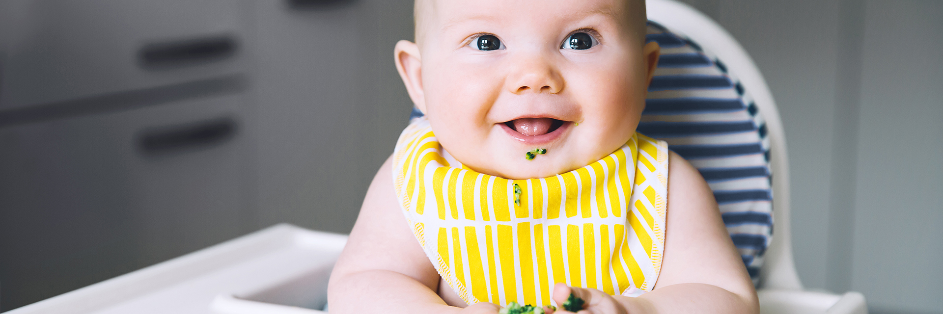 Baby with yellow bib in highchair