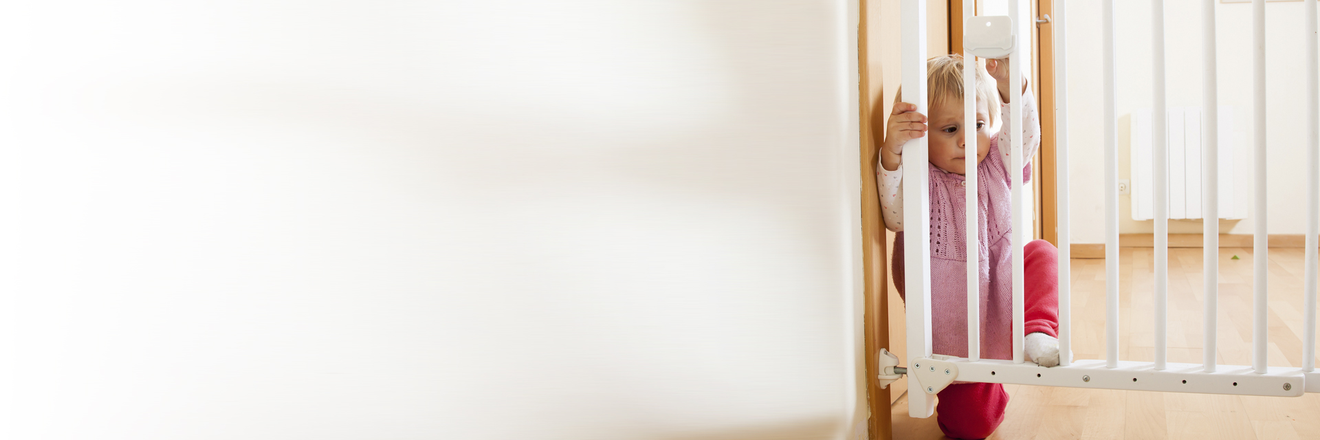 Baby standing behind baby gate