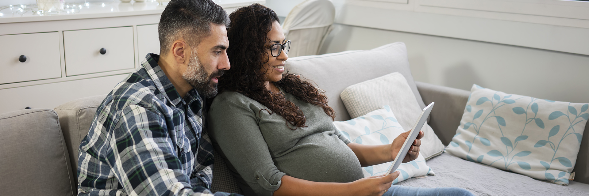 Couple sitting on couch looking at tablet