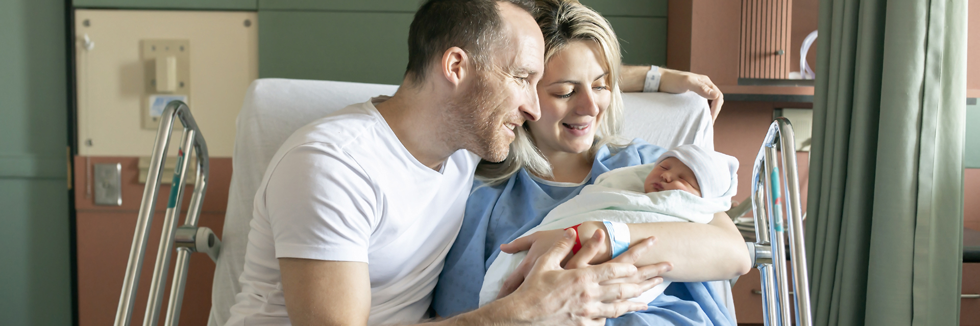 Man and woman in hospital bed with new baby
