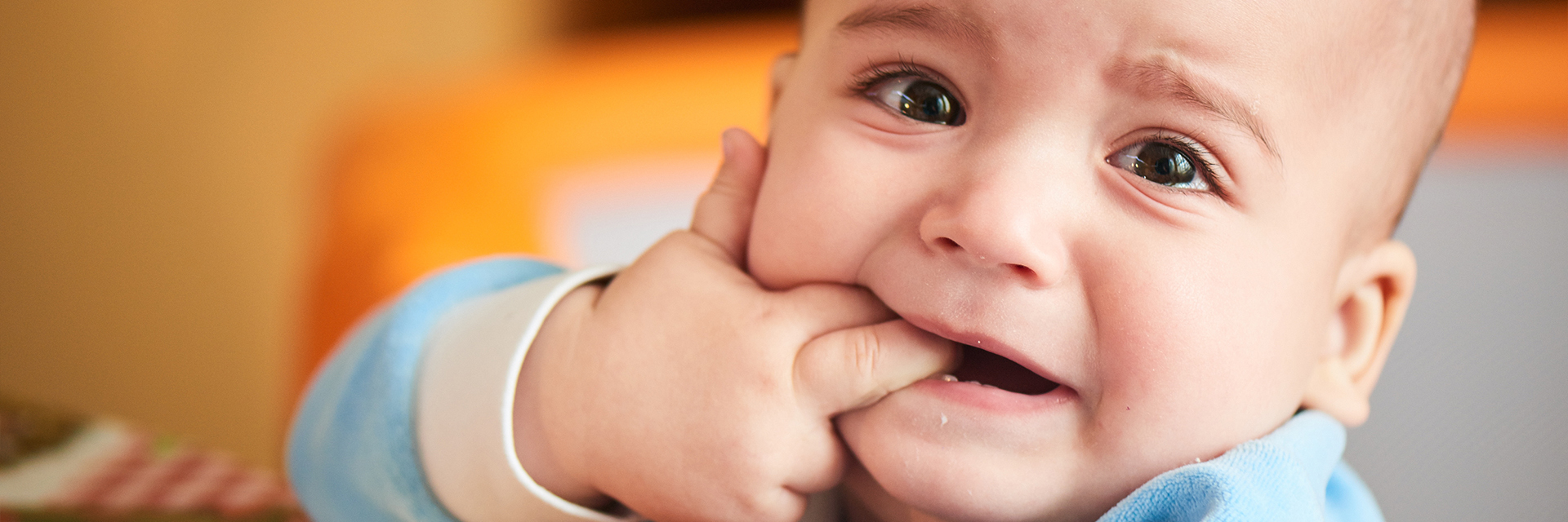 Crying infant with hand in mouth