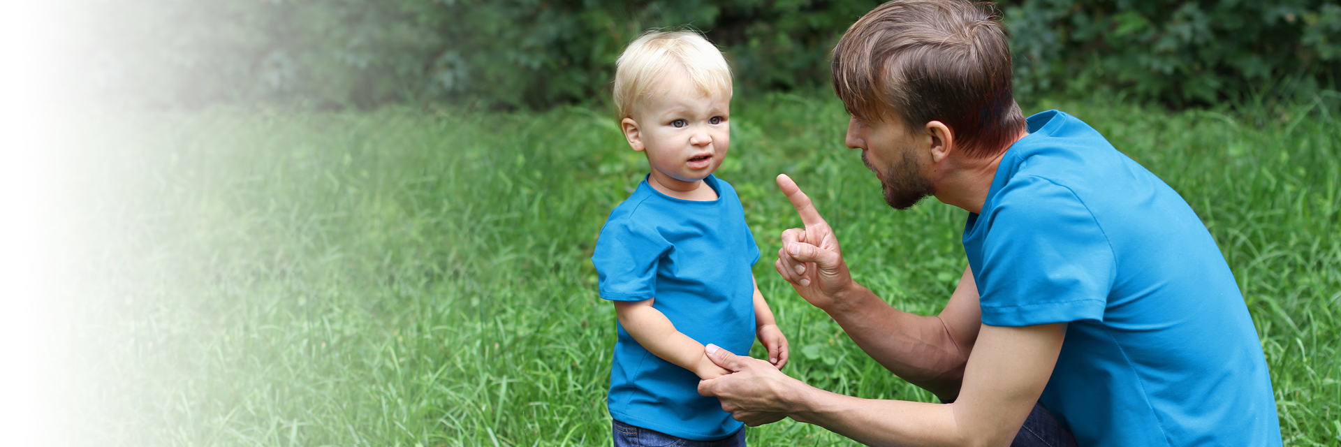 Dad talking to toddler boy outside