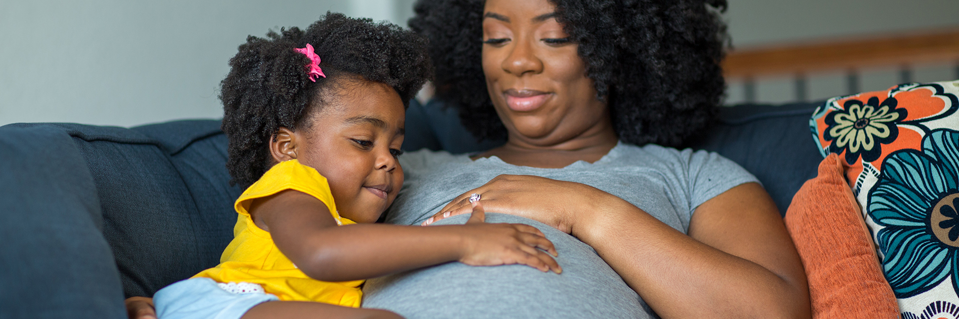 Daughter touching moms pregnant belly