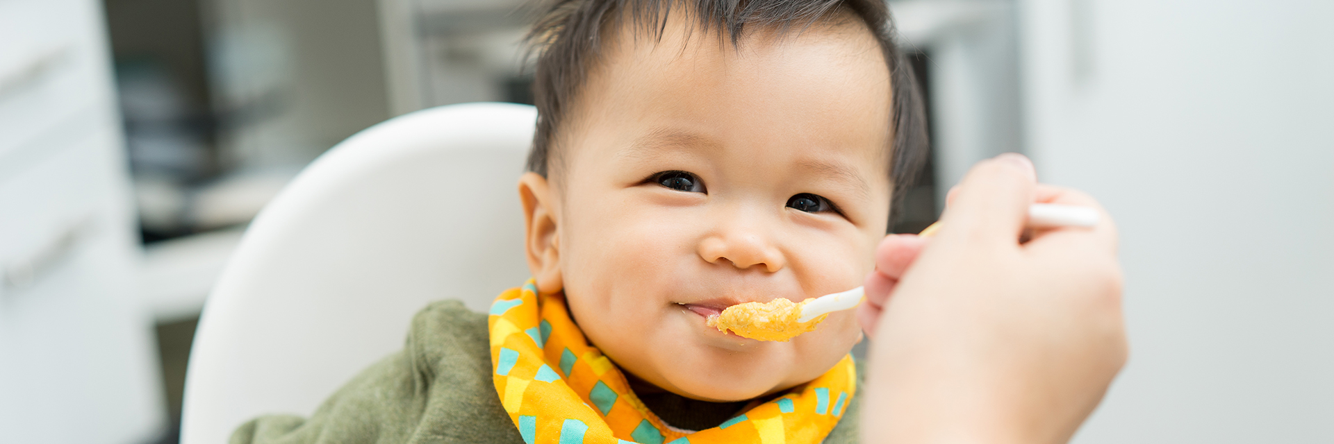 Infant boy eating in highchair