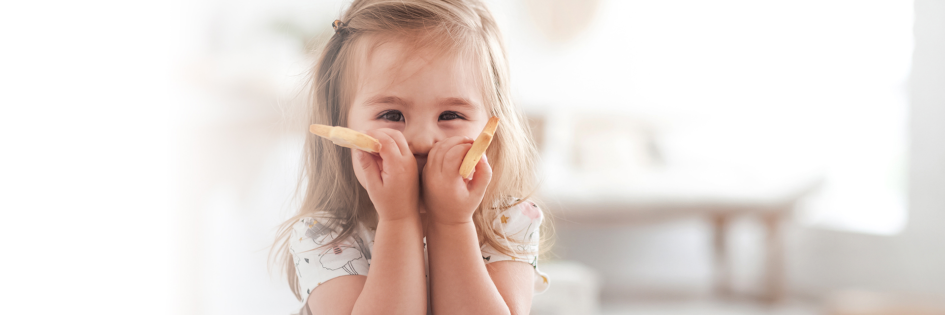 Little girl smiling holding finger foods