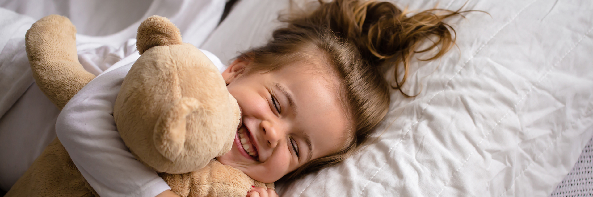 Little girl in bed holding plush toy