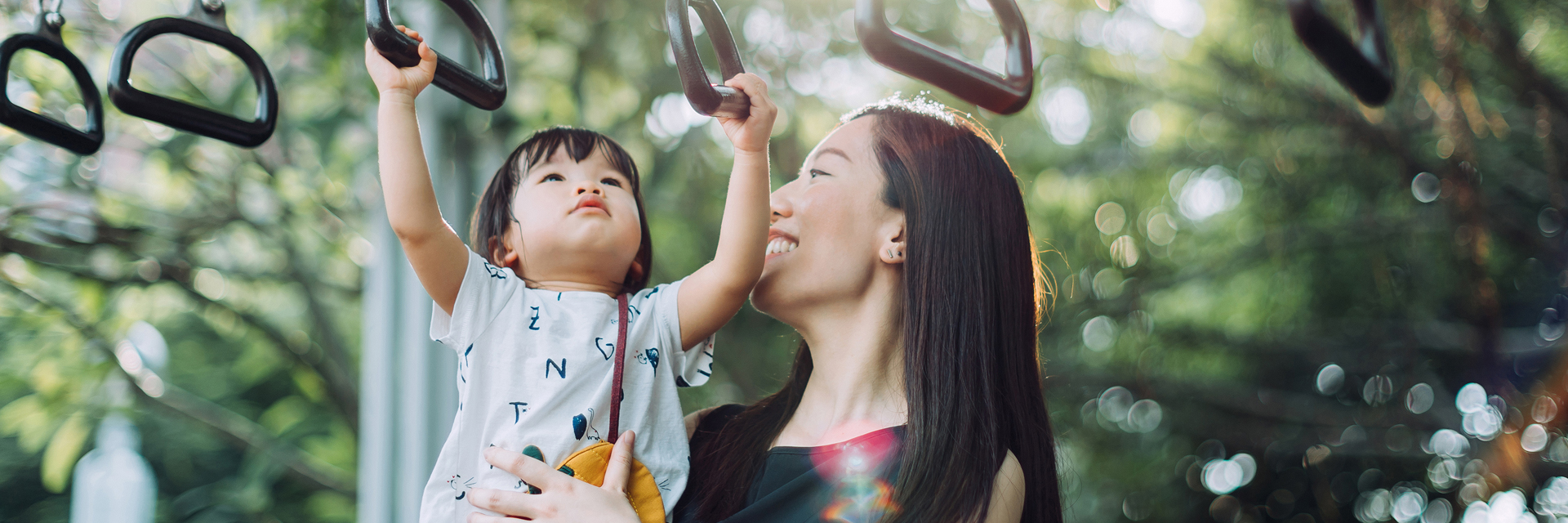 Mom and baby playing on playground rings