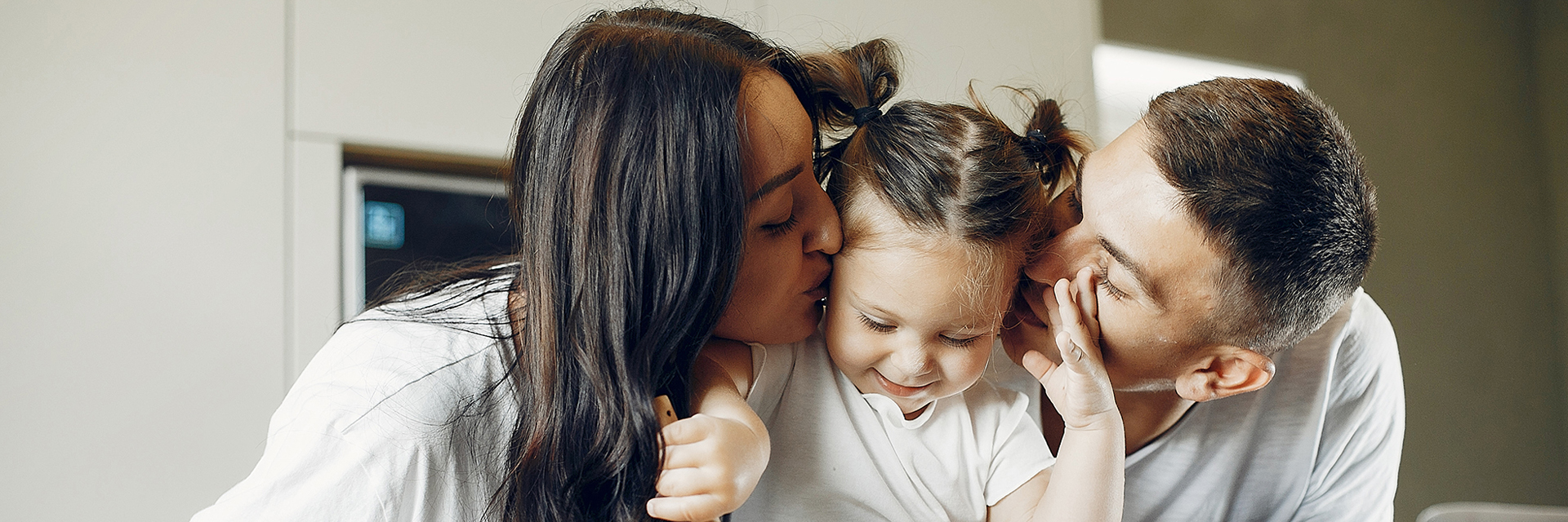 Parents kissing baby