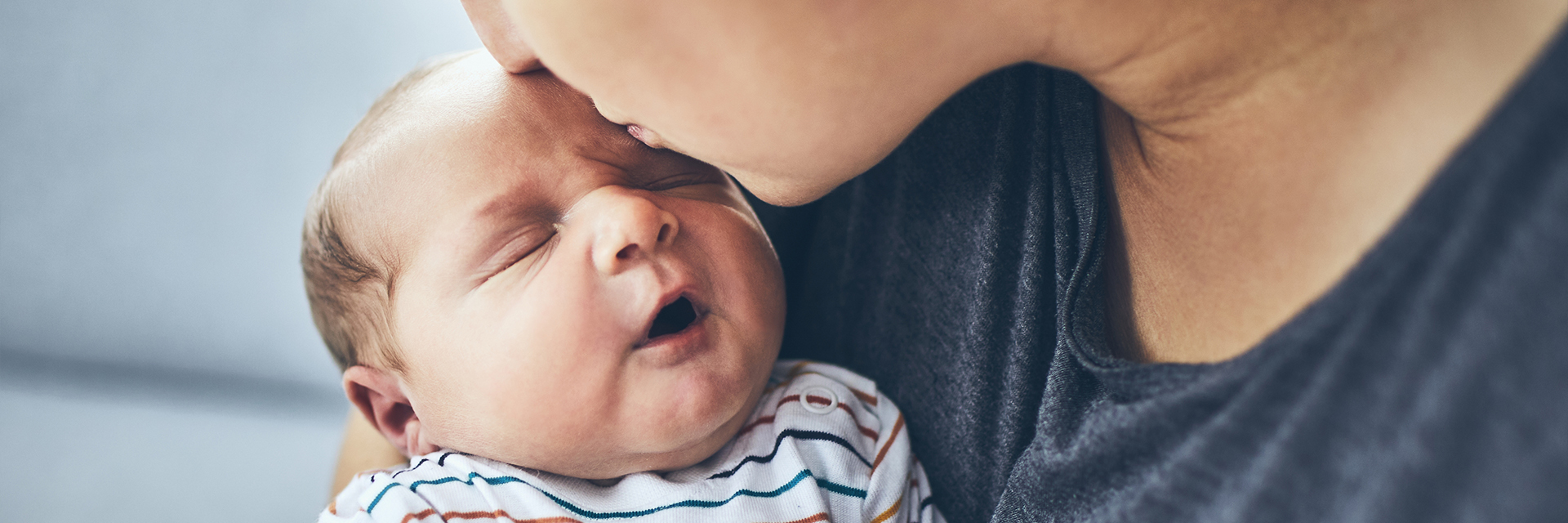Mom kissing fussy newborn
