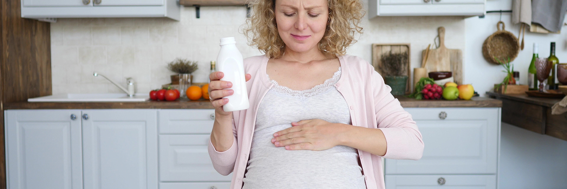 Pregnant woman grimacing holding bottle