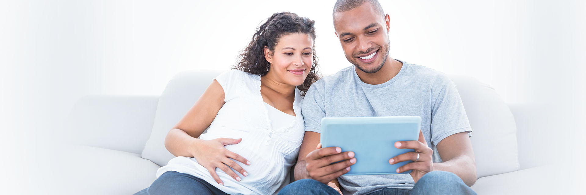 Pregnant couple smiling looking at a tablet