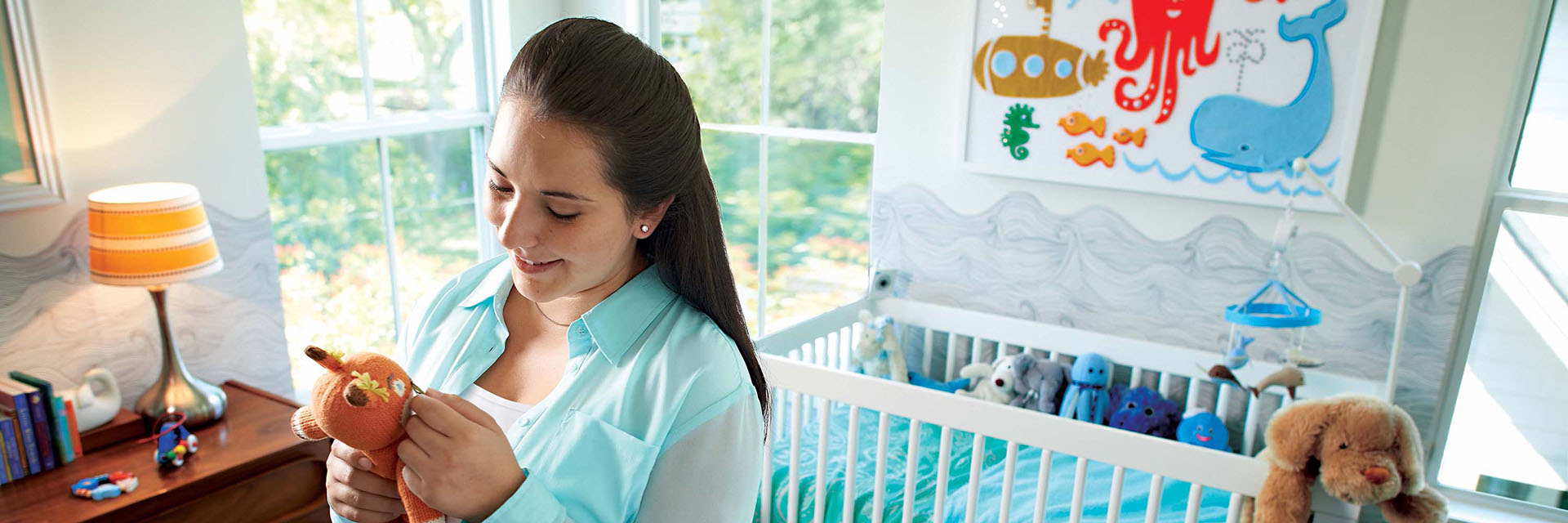 Pregnant woman in Nursery Holding Stuffed Toy