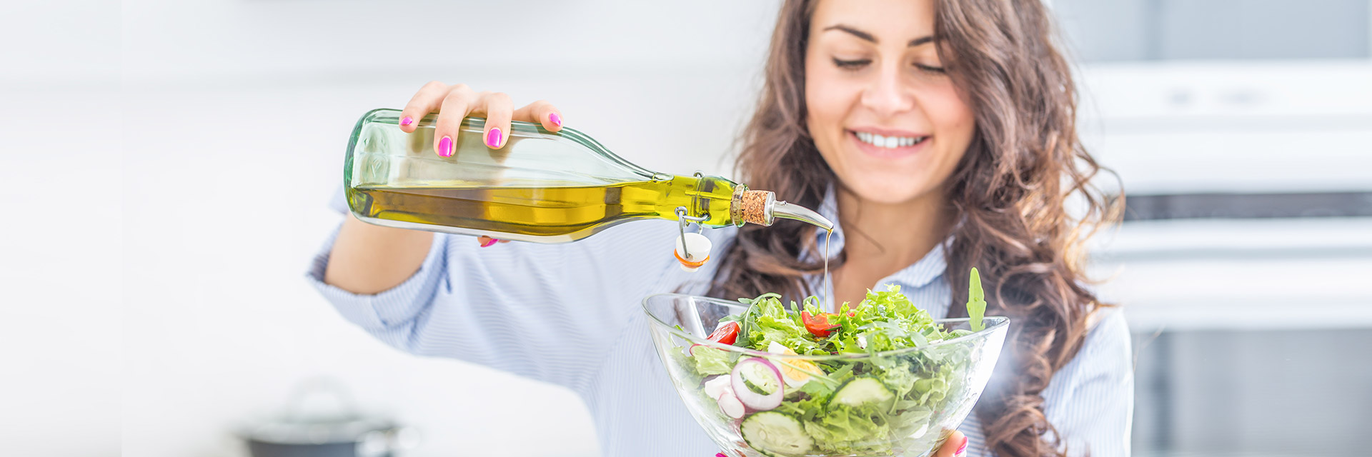 Woman putting oil on her salad