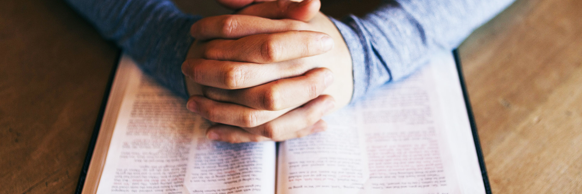 Interlaced Hands Over a Religious Book