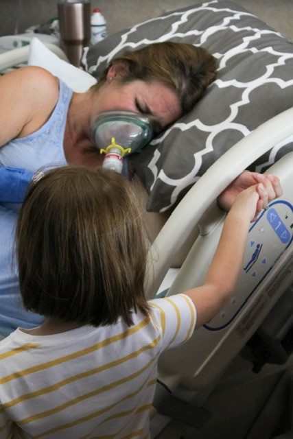 Nurse Allison Laviolette uses nitrous oxide during labor at Texas Health Cleburne while her daughter looks on.