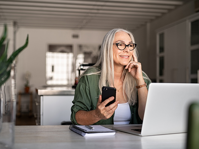 Woman using laptop and phone