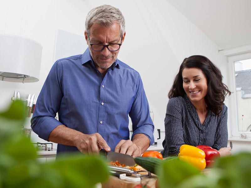Couple cutting food in kitchen